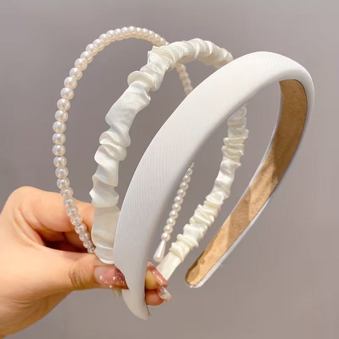 Un conjunto de tres diademas de tela para mujer en blanco con diseños de perlas