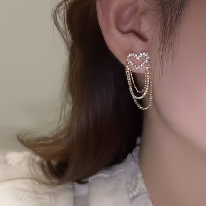 1 par de exquisitos y elegantes aretes de corazón hueco con borlas
