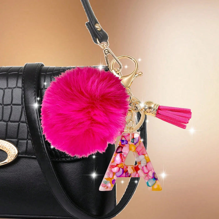 Un llavero con letra fucsia y pompón, diseñado exclusivamente para mujeres