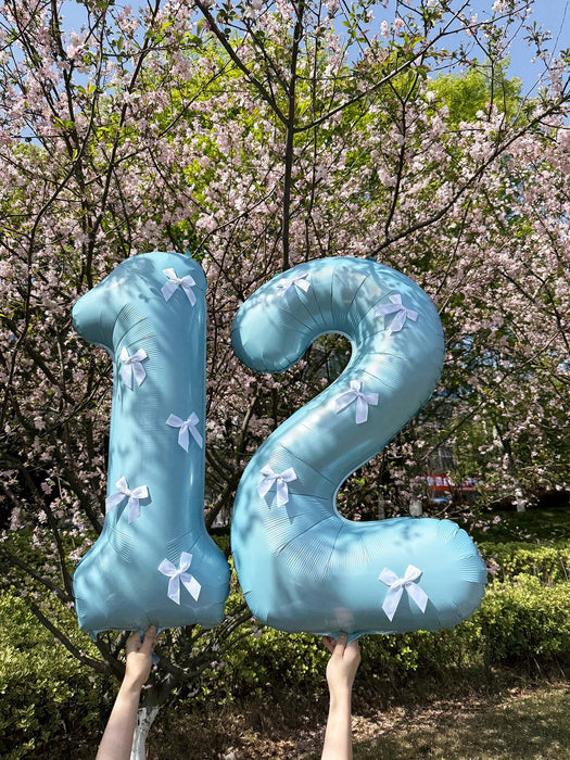 Globos de números azul claro con decoración de lazo blanco