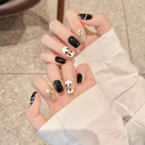 Uñas postizas press on de tipo "French PA" con diseño de nail art en blanco, negro y detalles brillantes