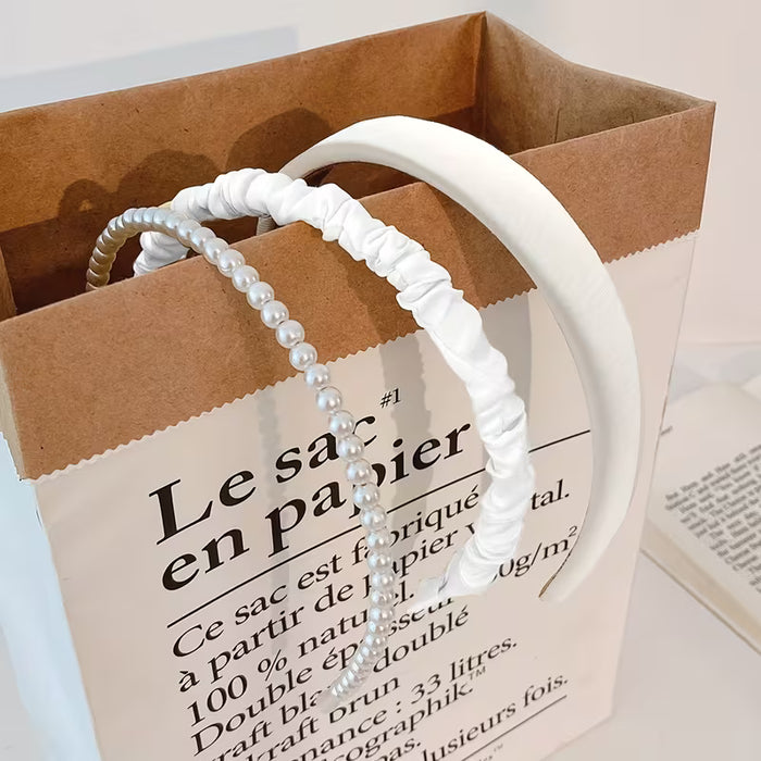 Un conjunto de tres diademas de tela para mujer en blanco con diseños de perlas