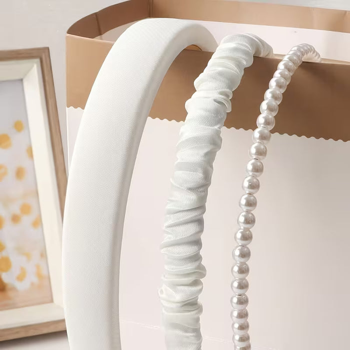 Un conjunto de tres diademas de tela para mujer en blanco con diseños de perlas